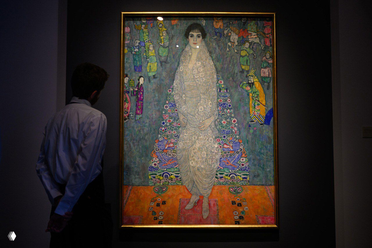 Картина «Портрет Элизабет Ледерер» Густава Климта в раме на стене выставки; посетитель рассматривает полотно в экспозиции музея.
