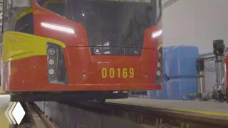 Крупный план передней части беспилотного трамвая «Львенок» с номером 00169 в депо, видны рельсы и оборудование вокруг вагона.