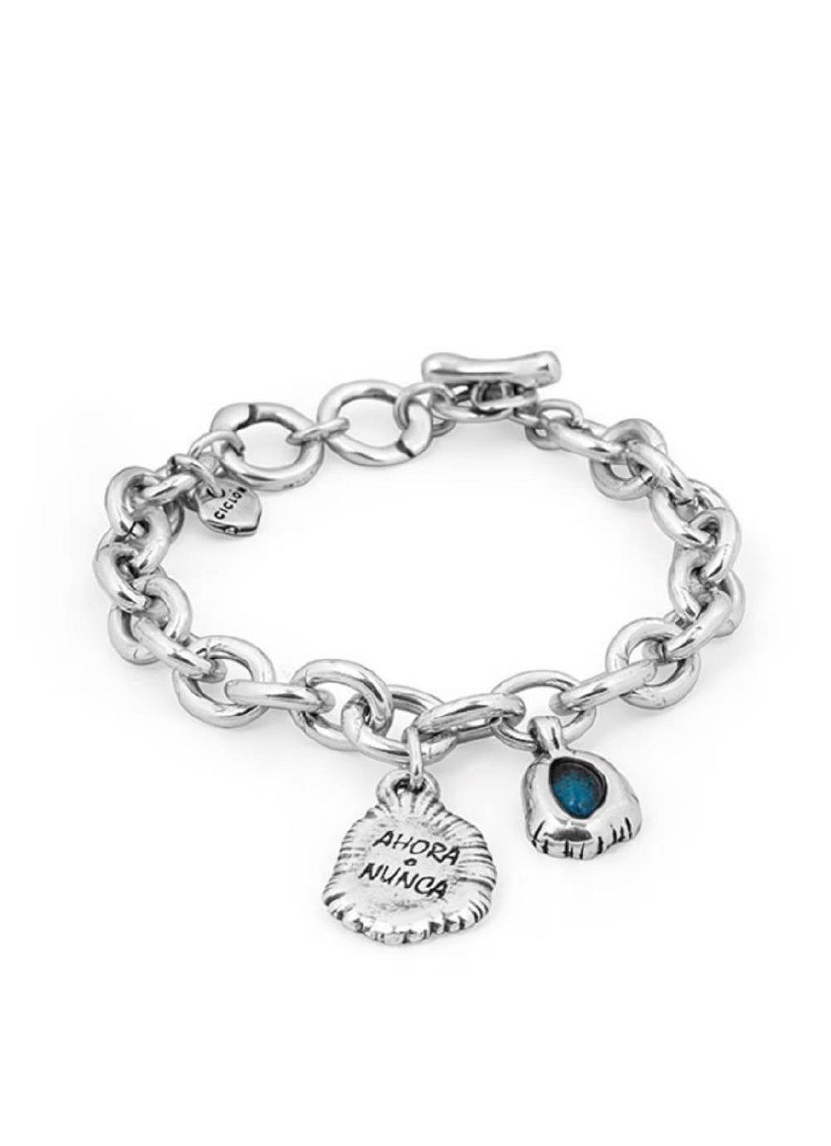 Крупный план нескольких тонких браслетов Ciclon с декоративными подвесками и кольцами-элементами, минималистичный белый фон подчёркивает детали.