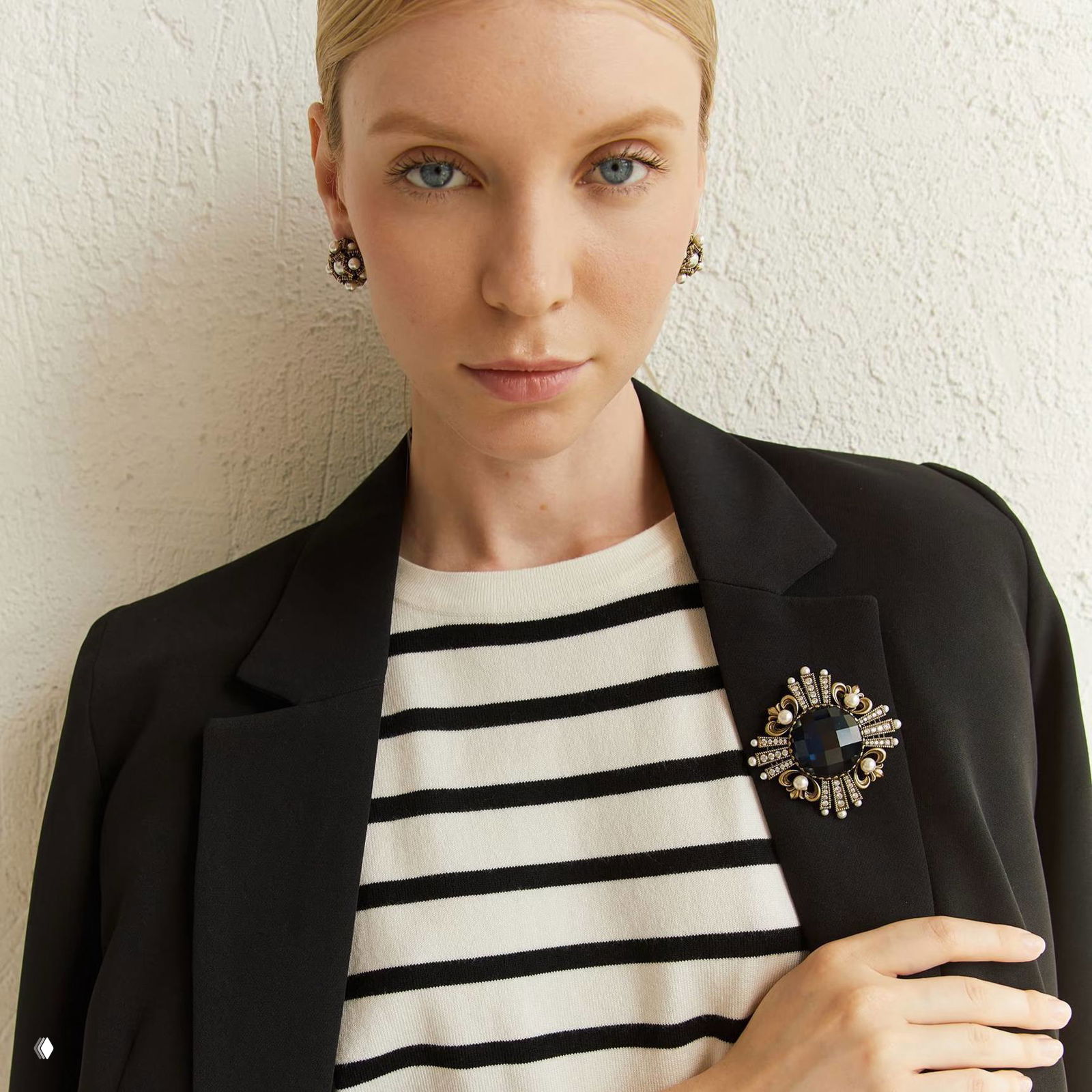 Модель в пиджаке носит брошь: образ показывает как акцентная брошь дополнит классический жакет и повседневный стиль.