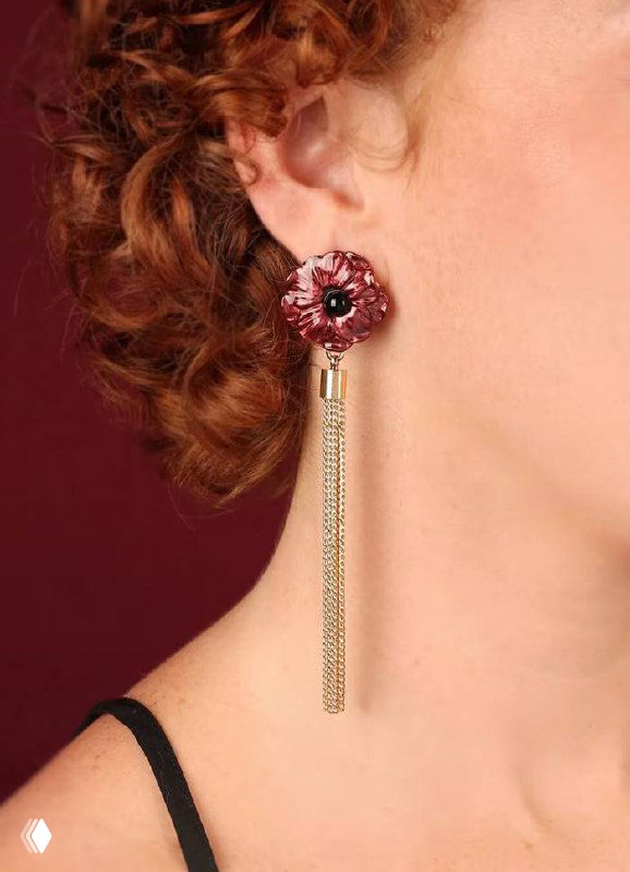 Крупный план серьги из коллекции CARMEN TARATATA на модели: красный эмалевый мак с тёмным центром, подвеска-кисточка из золотистых цепочек и аккуратная посадка на ухе.