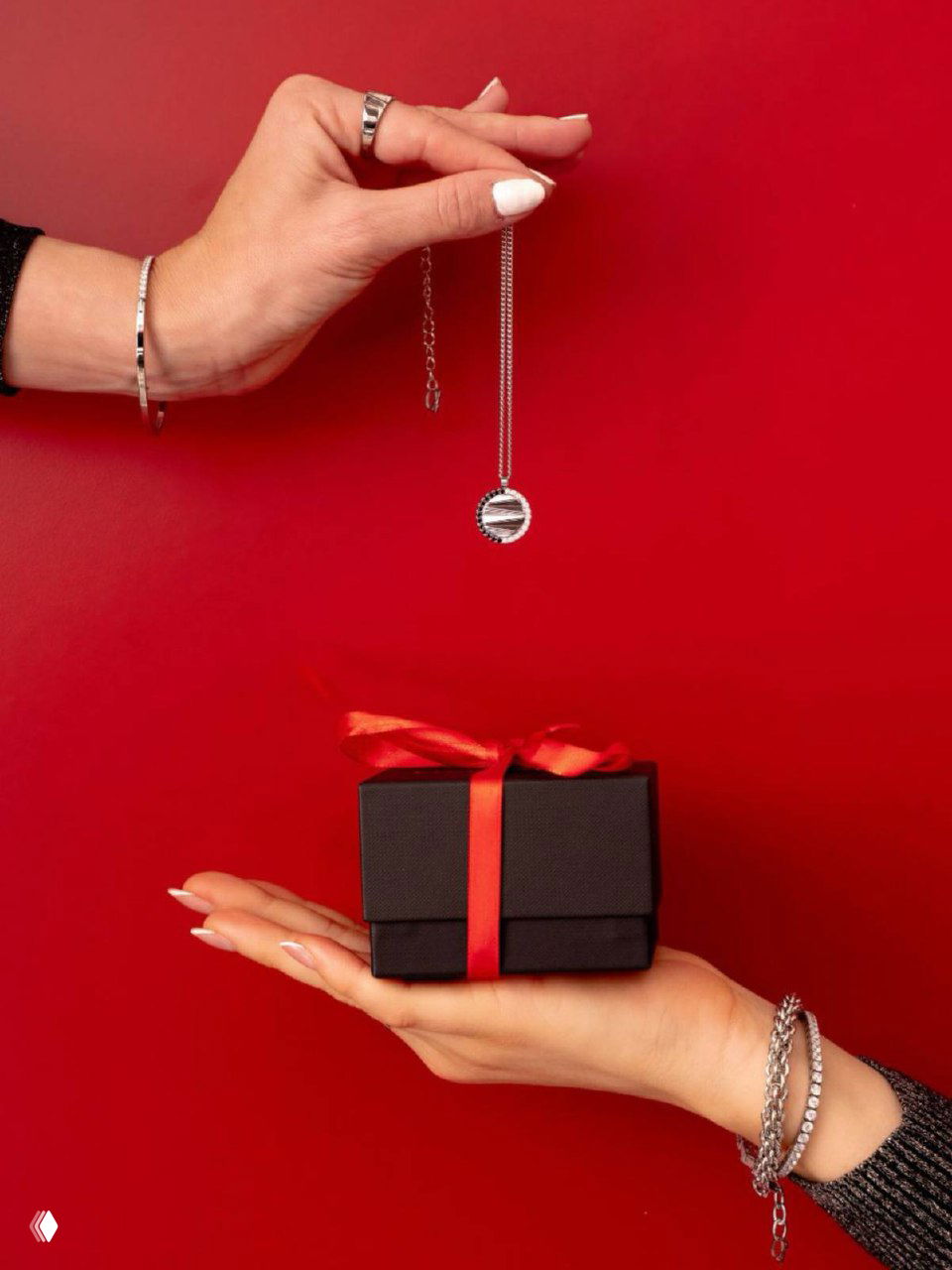 Рука с аккуратным маникюром держит подарочную коробку Coeur de Lion на насыщенном красном фоне — праздничный фотографический кадр.
