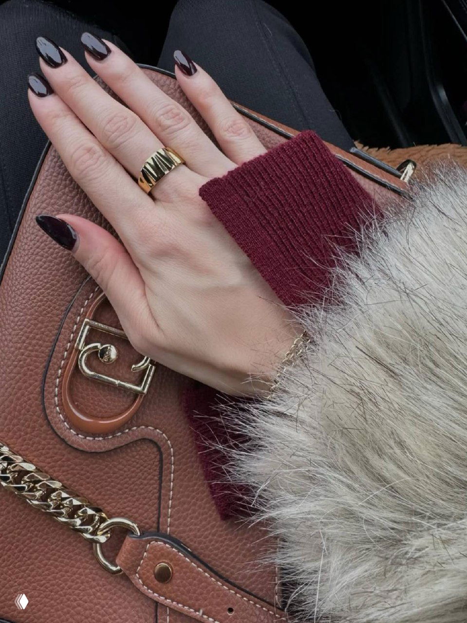 Рука в меховом манжете украшена браслетом рядом с кожаной сумкой и декоративными деталями — стильный аксессуарный кадр.