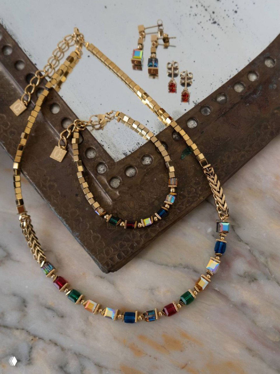 Колье и цепочки на мраморной поверхности: разноцветные бусины и металлизированные звенья в аккуратной демонстрации украшений.
