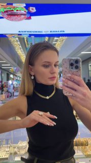 Селфи в зеркале: модель в черной одежде демонстрирует стильное колье и серьги бренда Claudio Canzian на фоне коридора торгового центра.