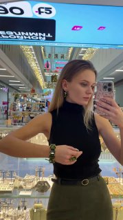 Селфи в зеркале — профиль женщины с серьгами и кольцом Claudio Canzian, на заднем плане прилавки Rosone и яркие рекламные вывески торгового центра.