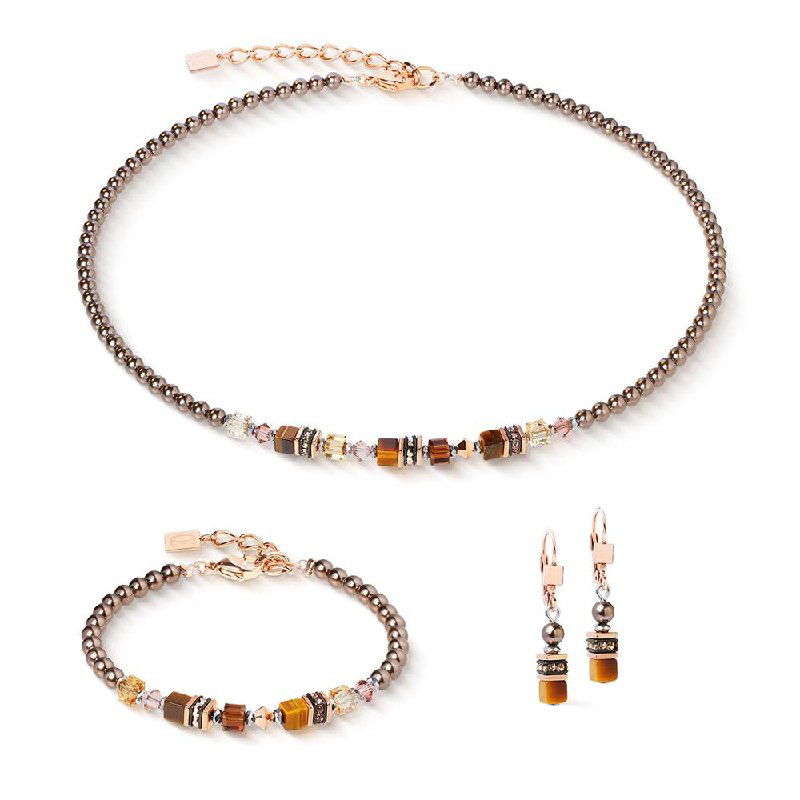 Крупный план цветного ожерелья с подвеской‑медальоном и браслетом из мелких изумрудных и персиковых бусин, студийная белая подложка.