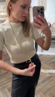 Женщина держит подвеску-ключ перед собой, видно всю длину цепочки и образ в зеркале — пример комбинации украшений.