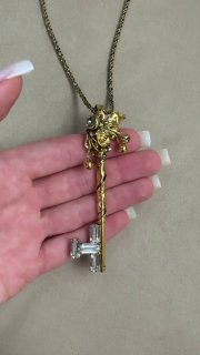 Детальный крупный план декоративного золотистого ключа с рельефной верхней частью и вставкой из прозрачных кристаллов на ладони.