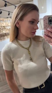 Модель в светлой одежде демонстрирует несколько ожерелий: длинная цепочка с ключом и ещё одно короткое украшение в многослойном образе.