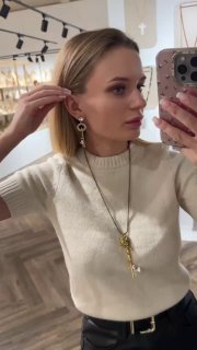 Селфи, на котором женщина поправляет серьгу и показывает крупным планом комбинированные украшения с подвеской-ключом в магазине Rosone.