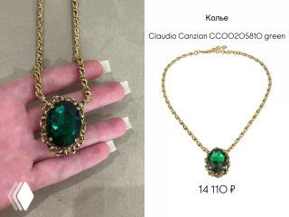 Крупный план золотого колье Claudio Canzian с крупным зелёным камнем, изделие показано на руке с белым маникюром рядом для масштаба и презентации.