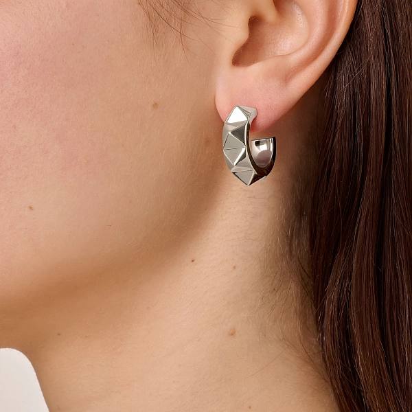 Серебристое серьго-кольцо DYRBERG KERN в профиль на ухе модели, демонстрация посадки украшения и фактуры металла в реальном образе.
