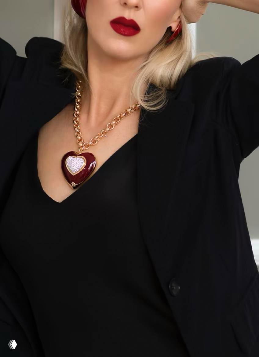 Студийный снимок красного сердцевидного кулона на золотой цепочке в кадре с моделью, акцент на форме и отделке изделия