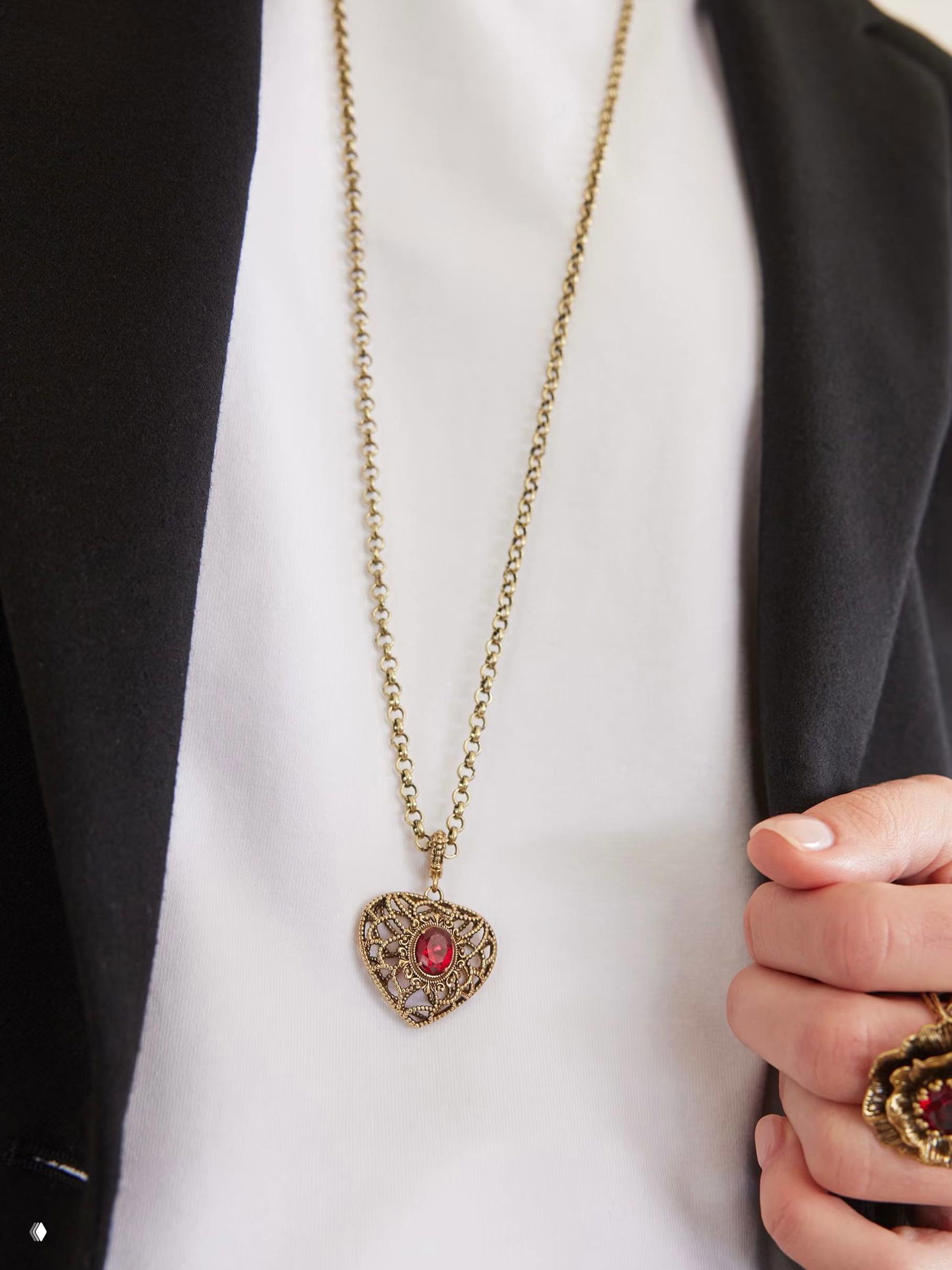 Белый фон, аксессуар AMORE ETERNO в витой ажурной форме: кольцо с крупным красным фианитом и филигранной решёткой, чистая студийная съёмка.