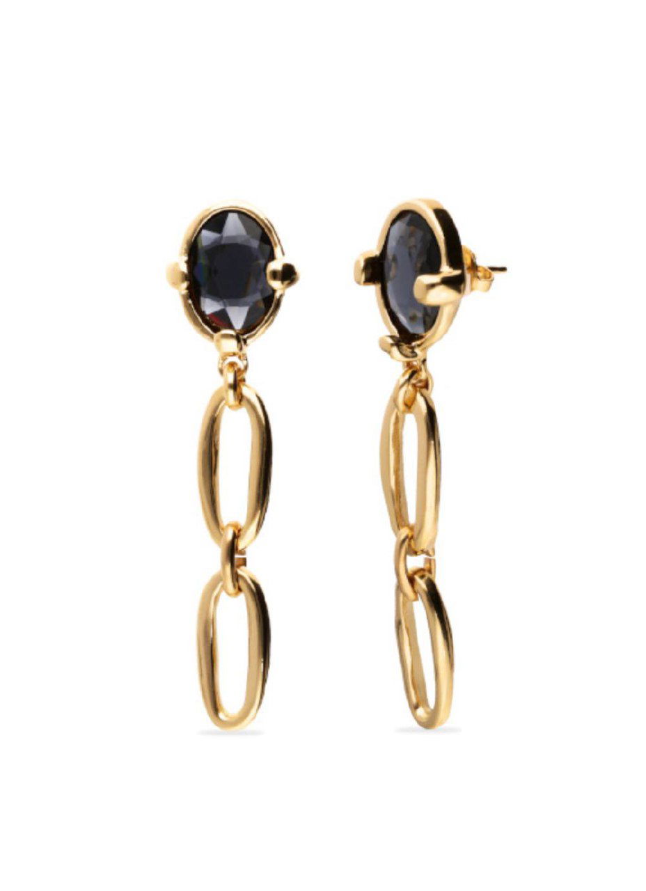 Детальный кадр серьг UNOde50 на белом фоне: удлинённые звенья цепочки, чёрные кристаллы и контрастный минимализм в дизайне.