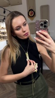 Модель демонстрирует подвеску на длинной цепочке в зеркальном селфи в торговом зале; видно общий вид украшения и посадку на шее.