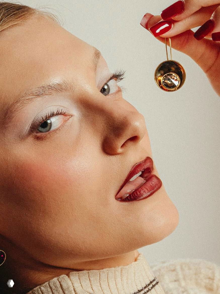Крупный план женского лица с серьгой в форме чашечки и крупным камнем — фокус на качестве отделки и эстетике украшений KALLIOPE.