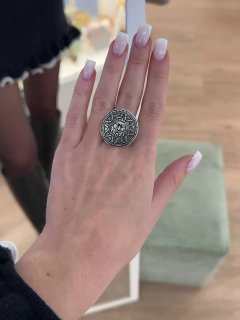 Крупный план руки с декорированным крупным серебряным кольцом Ciclon; маникюр на фоне интерьерного коврика в магазине Rosone.