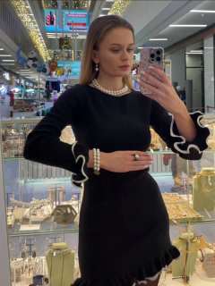 Крупный снимок модели в чёрном платье у зеркала с бусами и браслетом Fiore di Firenze; видна витрина с украшениями в магазине.