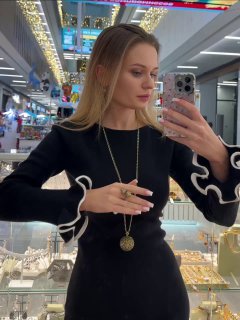 Модель в профиль перед зеркалом демонстрирует медальон и колье Fiore di Firenze; на заднем плане витрины и магазинная подсветка.