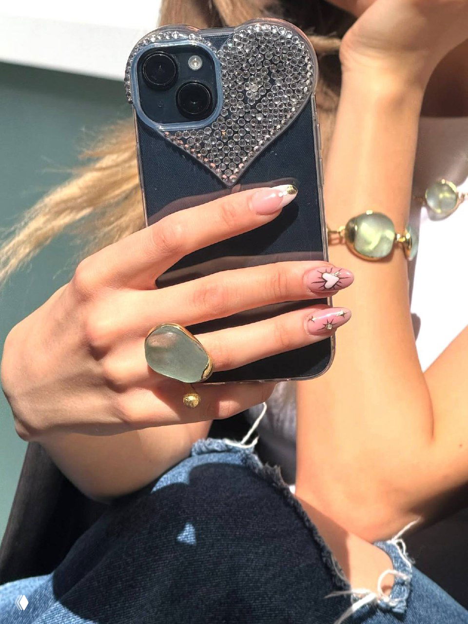 Рука держит смартфон и демонстрирует кольцо и браслет: нежный летний снимок с акцентом на крупное каменное кольцо и браслет из коллекции.