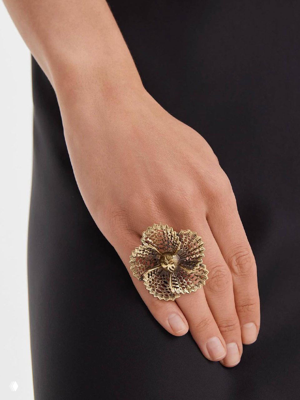 Деталь руки с крупным дизайнерским перстнем на фоне черной ткани — художественный фешн‑кадр для каталога украшений.