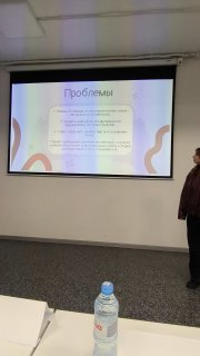 Кадр с демонстрацией слайдов и побочной активностью в аудитории: обмен мнениями между участниками и судьями.