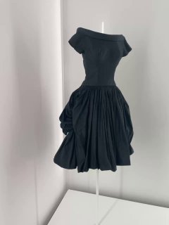 Фрагмент витрины с жакетом и платьями, видны лейблы дизайнеров и контраст белых экспозицонных стен с одеждой чёрных тонов.