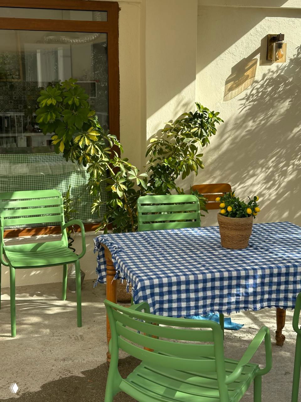 Солнечный уголок с зелеными стульями и скатертью в клетку на террасе — спокойная утренняя сцена маленького кафе или двора в Турции.