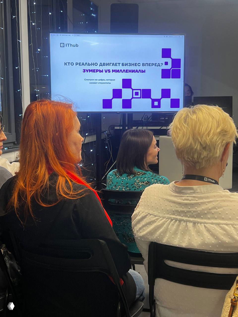 Слайд на экране с заголовком о влиянии зумеров и миллениалов на бизнес; в переднем плане слушатели во время презентации.