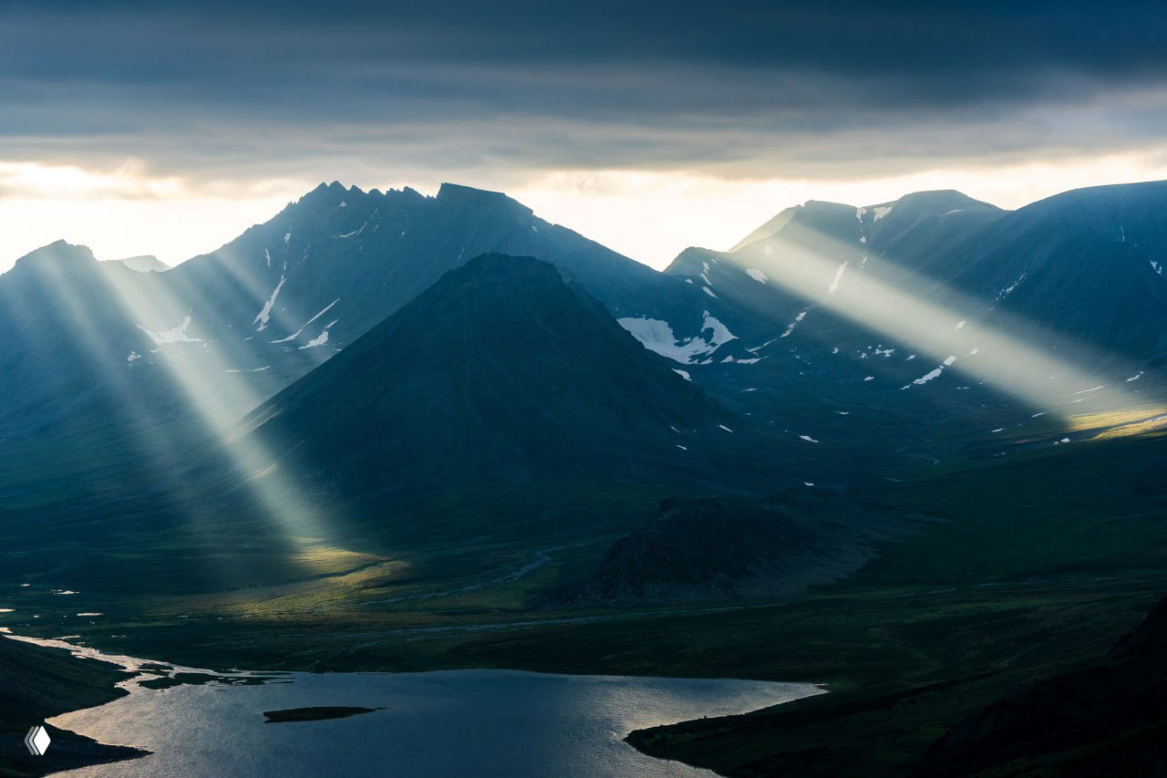 Горный пейзаж с озером и солнечными лучами сквозь облака; иллюстрация, символизирующая выбор пути и новый этап в Европе.