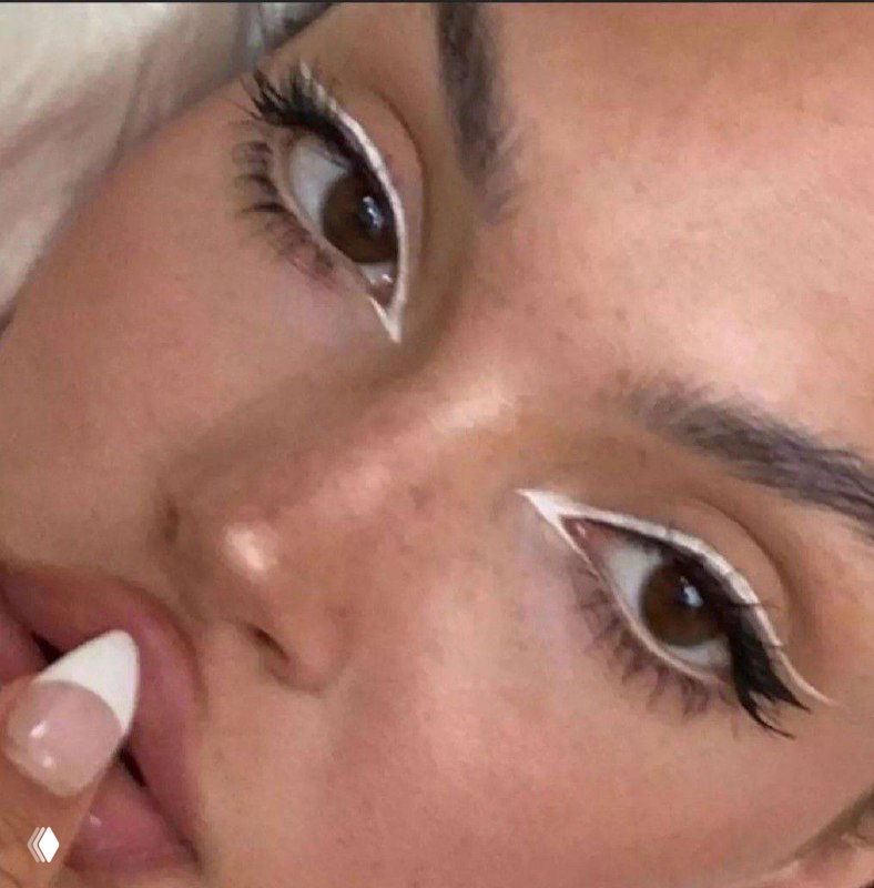 Крупный план лица с акцентом на глаз и выразительную стрелку, частично виден нюдовый маникюр — пример праздничного макияжа для новогодней ночи.