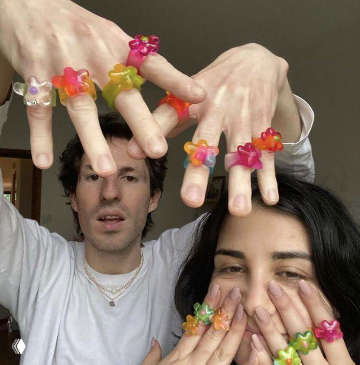 Двое людей демонстрируют множество ярких желейных колец на пальцах — маленькие прозрачные украшения как массовый тренд среди зумеров и миллениалов.