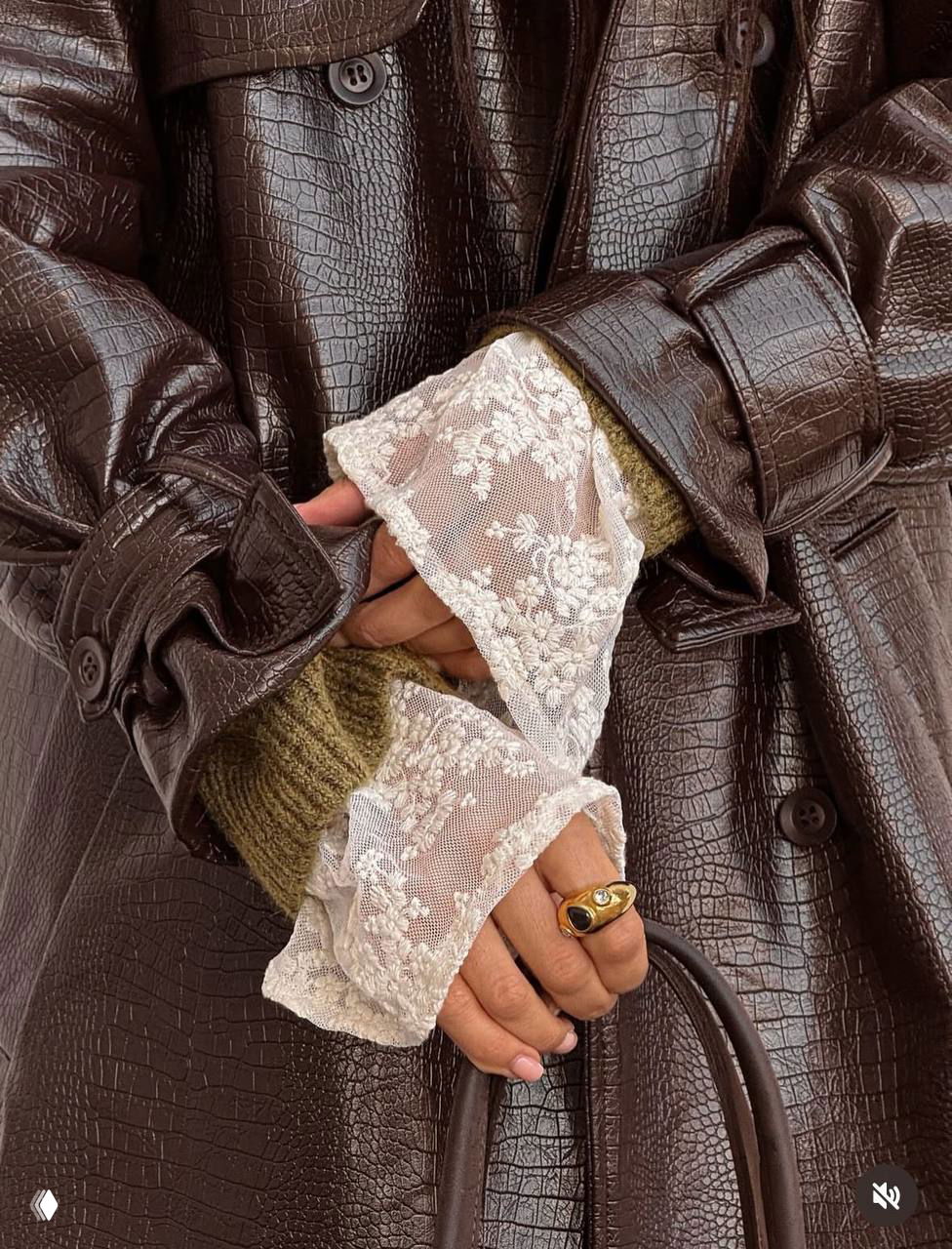 Шерстяные митенки, выступающие кружевные запястья и большой золотой перстень на фоне тёмного кожаного пальто — деталь образа.