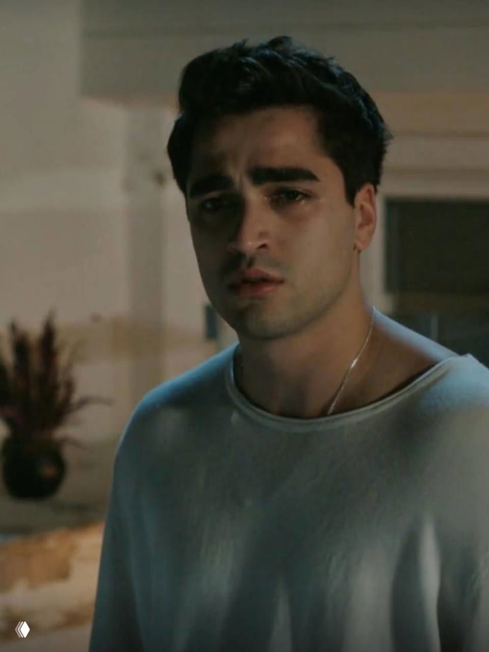 Крупный план молодого актёра из сериала «Зимородок»: печальное выражение лица, влажные глаза и интерьер на заднем плане.