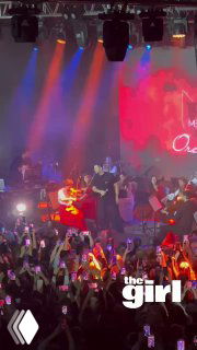 Вертикальное видео с концерта: артист и гитарист на сцене, разноцветная подсветка, толпа фанатов с поднятыми смартфонами.