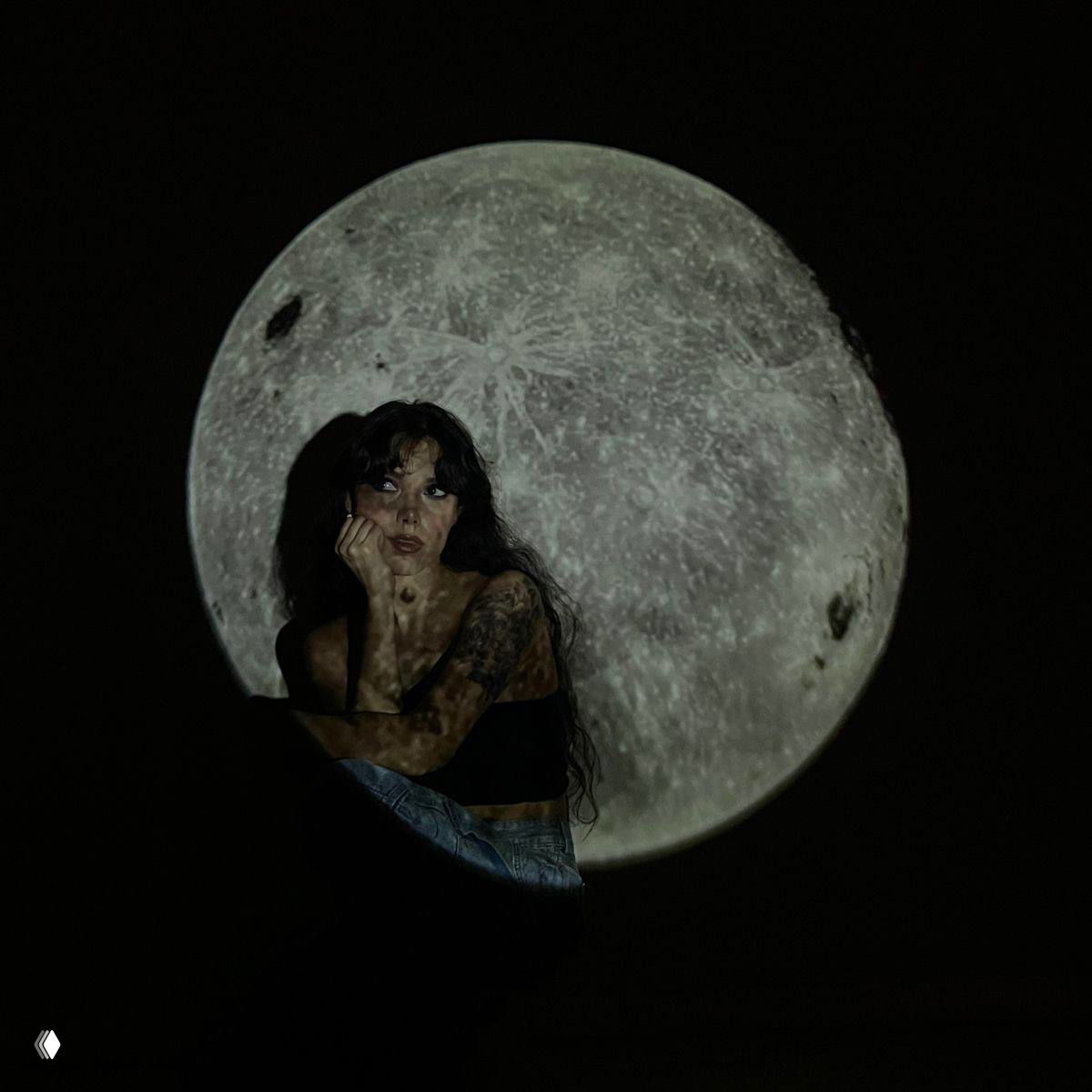 Женщина на тёмном фоне перед крупной проекцией полной луны; кадр иллюстрирует тему Полнолуния в Тельце и астрологию.