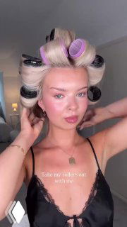 Модель с бигуди на голове показывает процесс формирования крупных локонов и эффект выгоревших прядей после укладки.