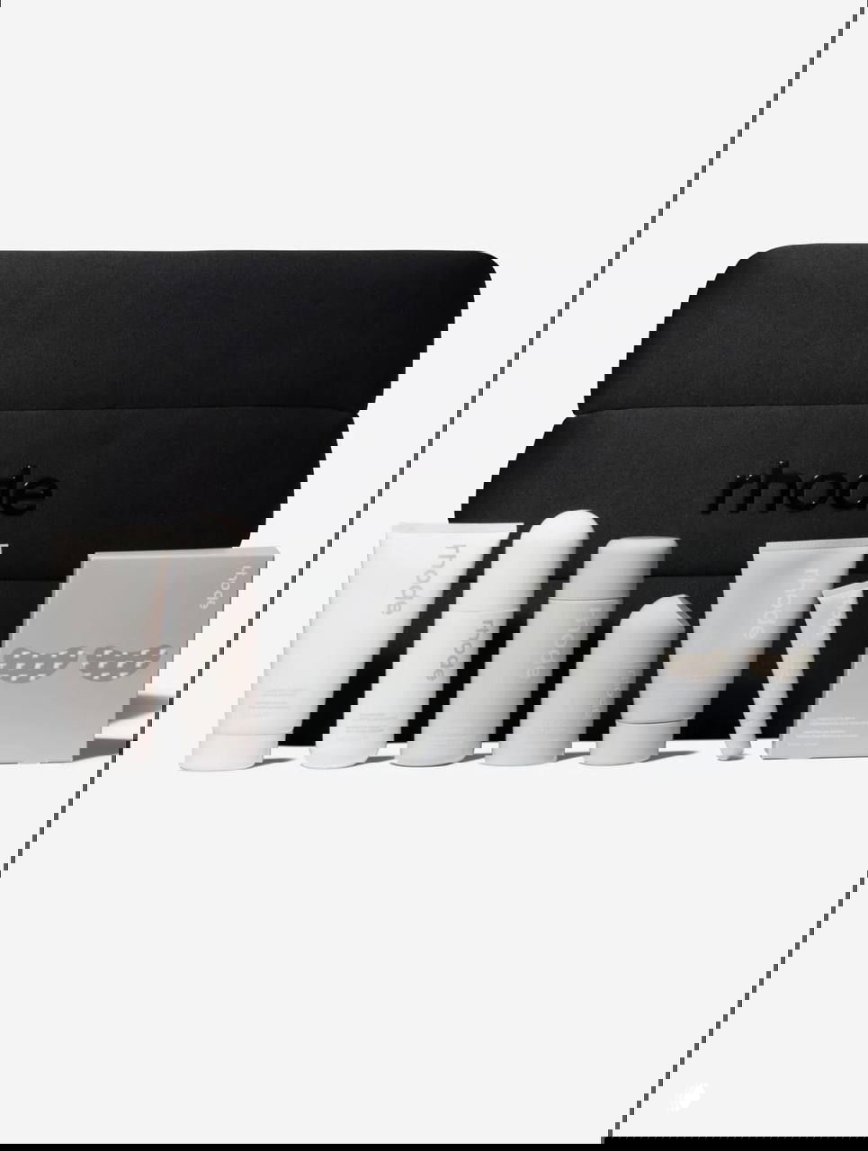 Набор Rhode The Birthday edit: несколько косметических средств и чёрная стёганая сумка с тиснёным логотипом rhode на светлом фоне.