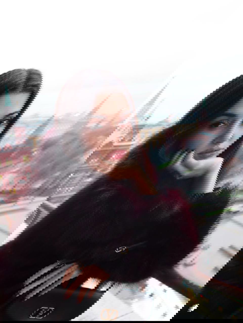 Портрет женщины на фоне городской панорамы: тёплый меховой жакет, взгляд в камеру, панорама города за балконом в туманную погоду.