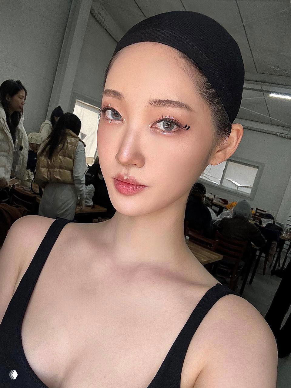 Крупный портрет с ярким мейком на бьюти-шоу: лицо модели с выразительным глазным макияжем и ровной кожей в гримерной обстановке, бэкстейдж.