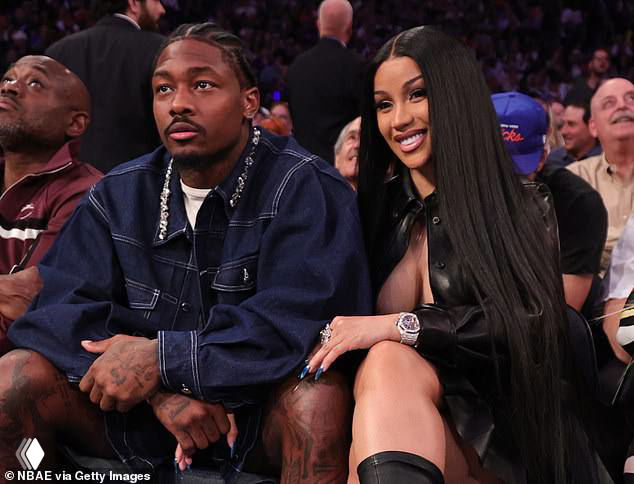 Карди Би и Стефан Диггс сидят рядом на трибуне во время матча; кадр показывает пару в неформальной обстановке.