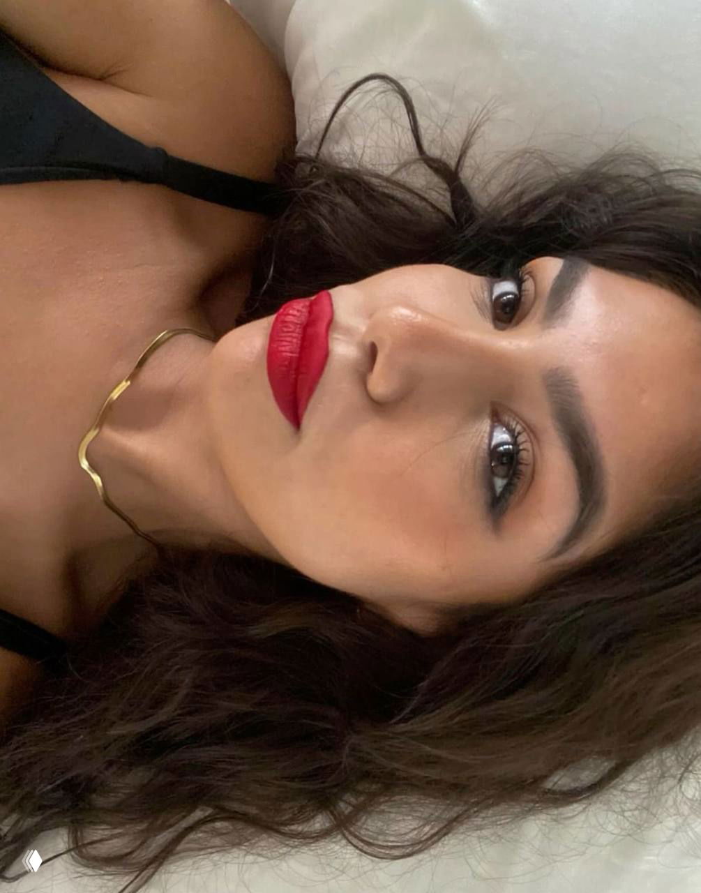 Горизонтальный портрет модели с тёмными волнистыми волосами и насыщенной красной помадой, лицо в естественном свете, взгляд в камеру.