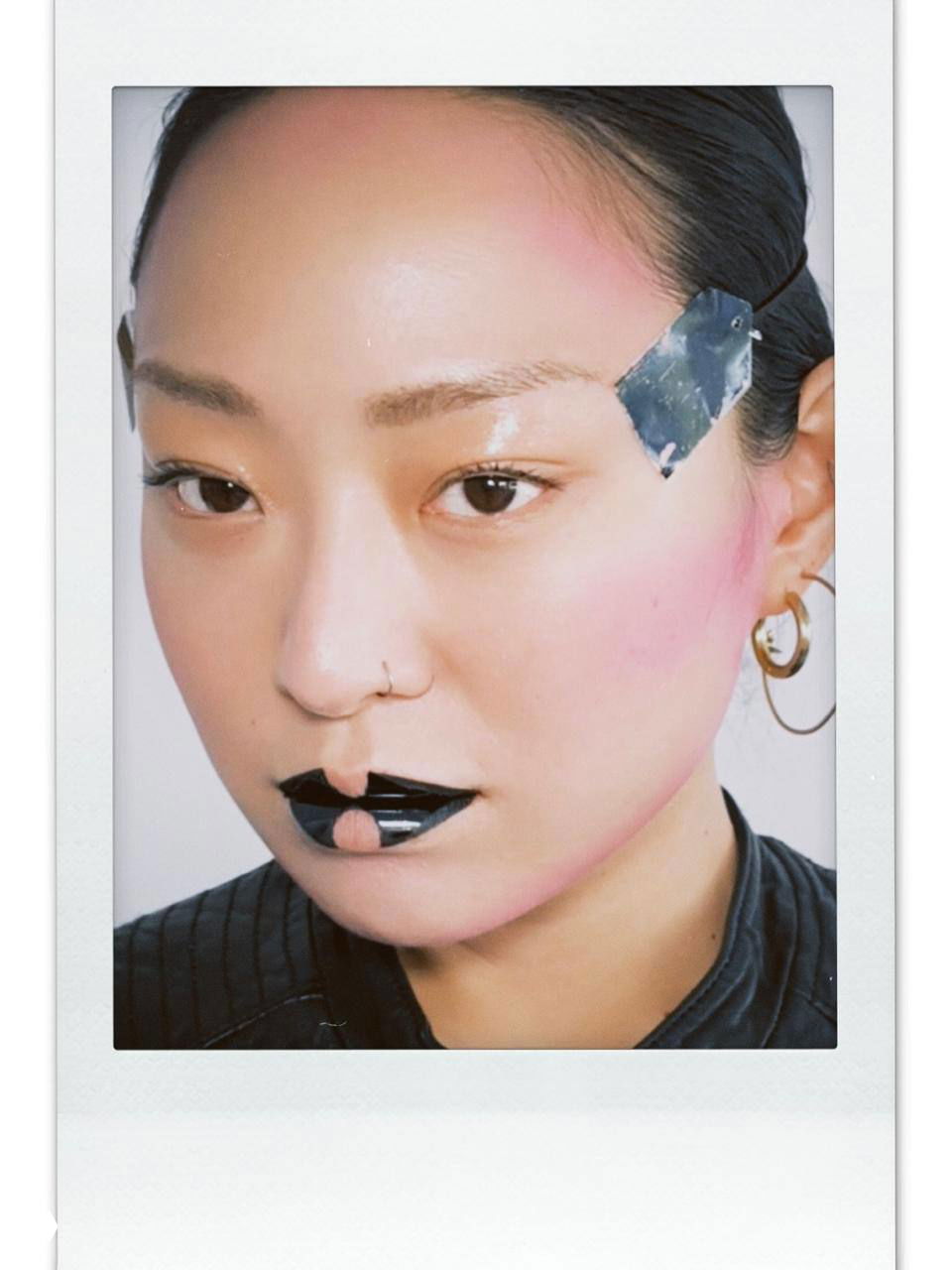 Фотополароид с экспериментальным макияжем: черная графичная помада и необычные элементы на лице модели, творческий образ визажиста.