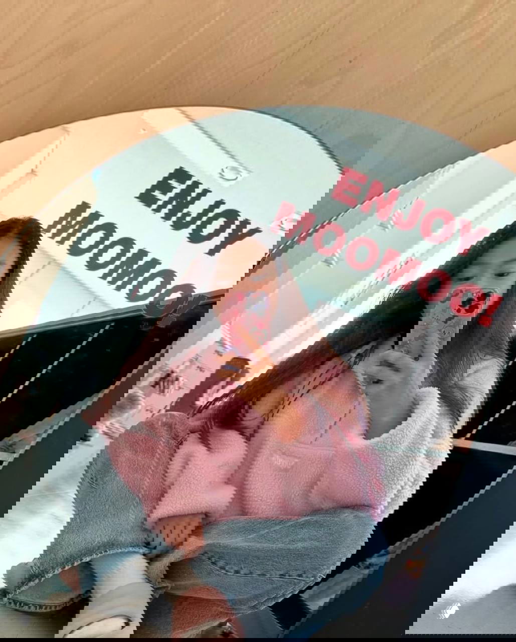 Зеркальное селфи девушки в розовой пушистой куртке и джинсах в интерьере магазина или студии; мягкая текстура и повседневный комфортный образ.