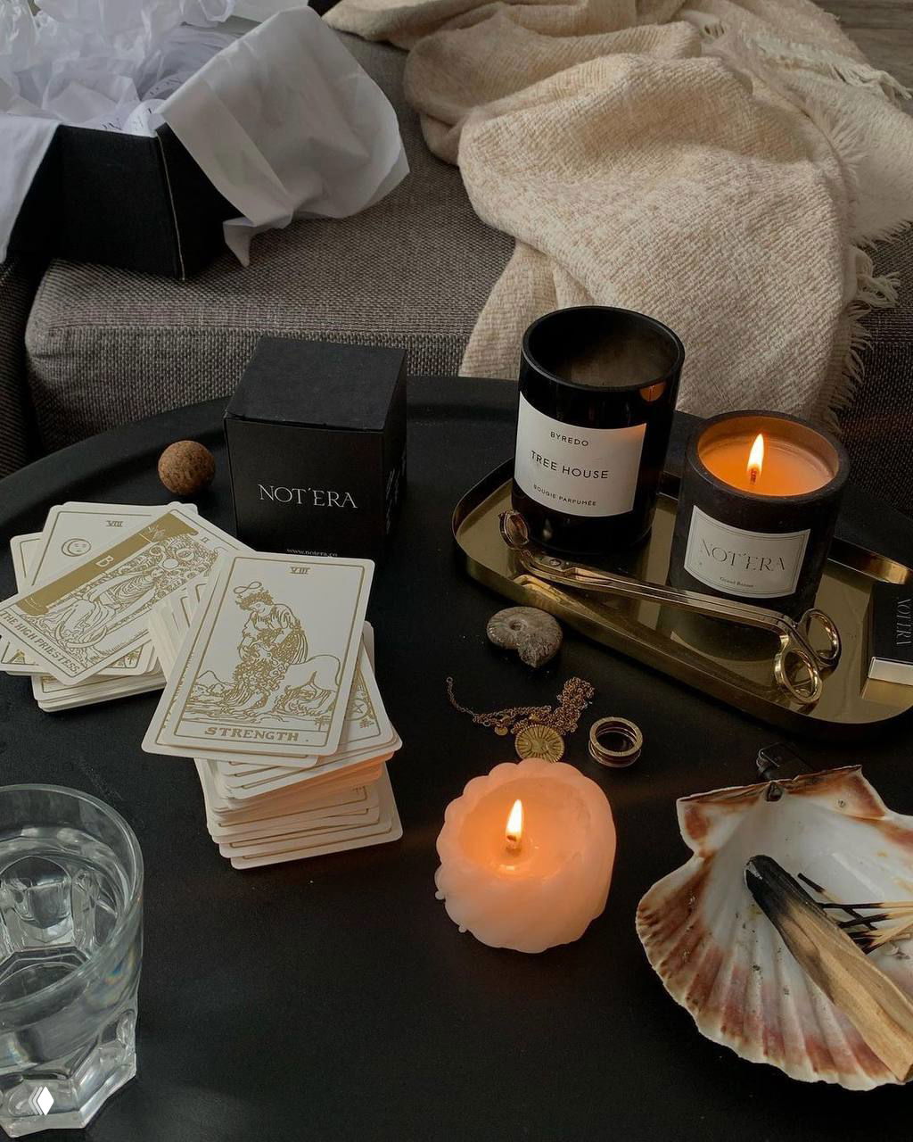 Интерьерная сцена с картами Таро, горящей свечой и ароматическими свечами на подносе; атмосферный натюрморт в тёплой цветовой палитре.