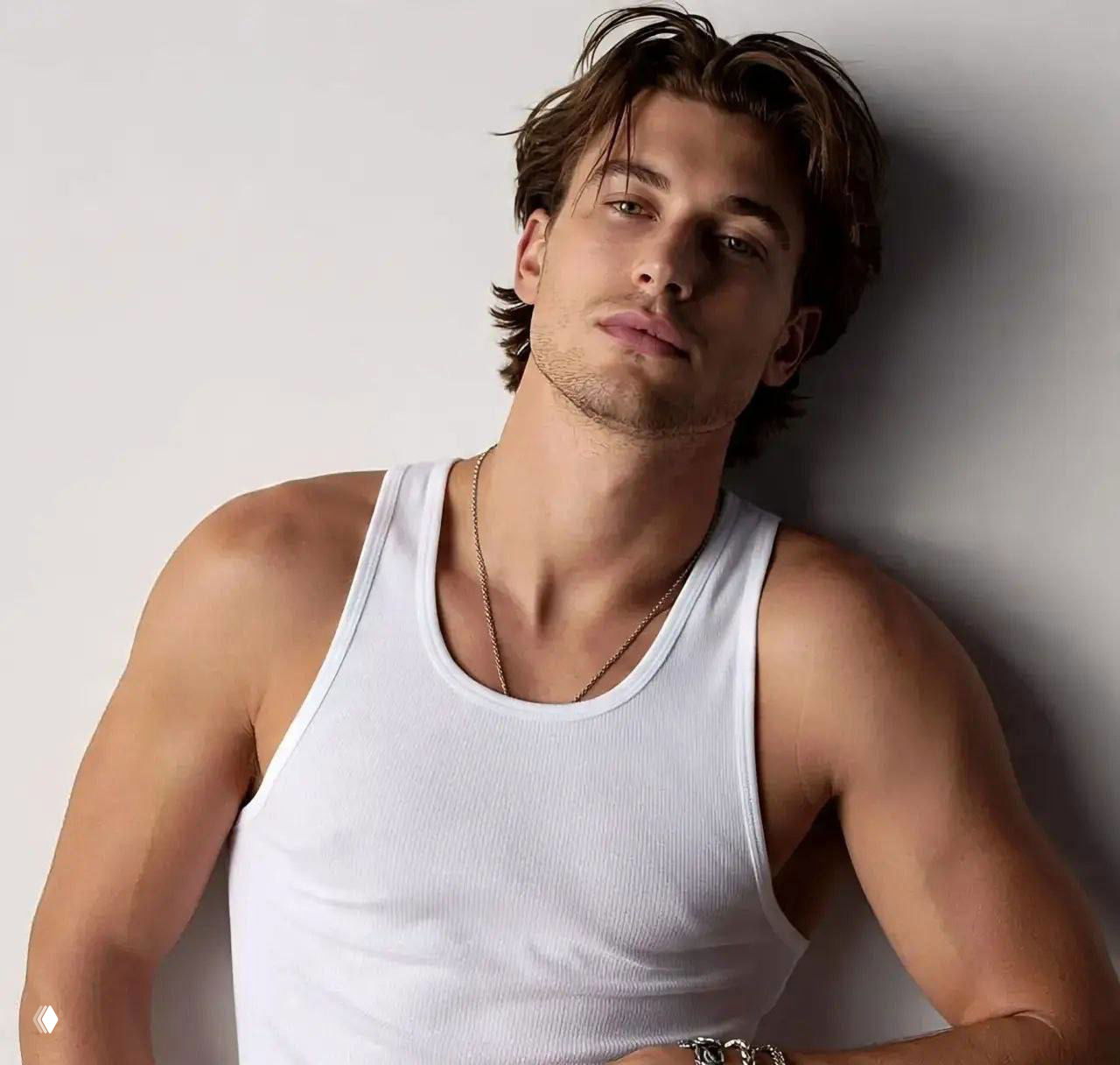 Студийный портрет мужчины в белой майке и ожерельем, нейтральный фон, акцент на лице и плечевом торсе, редакционная съёмка