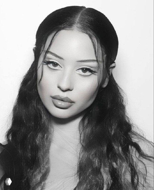 Чёрно‑белый студийный портрет молодой девушки с выразительным макияжем: чёткие стрелки на глазах, глянцевые губы и аккуратно уложенные волосы в мягком освещении.