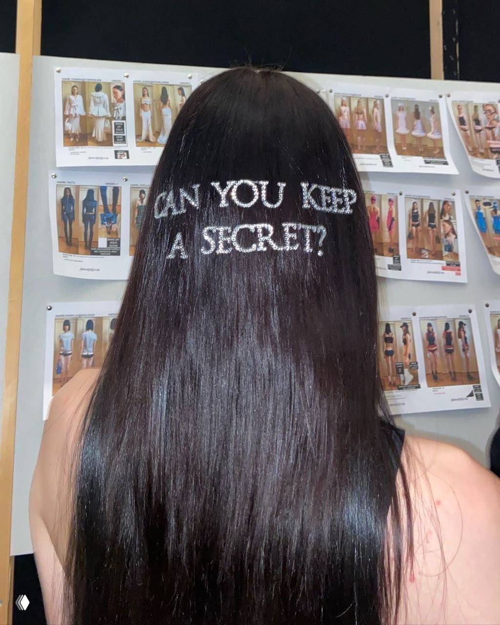 Вид сзади на длинные тёмные волосы с декоративной вышивкой «CAN YOU KEEP A SECRET?»; на заднем плане заметны доски с образцами и фотографиями для вдохновения.